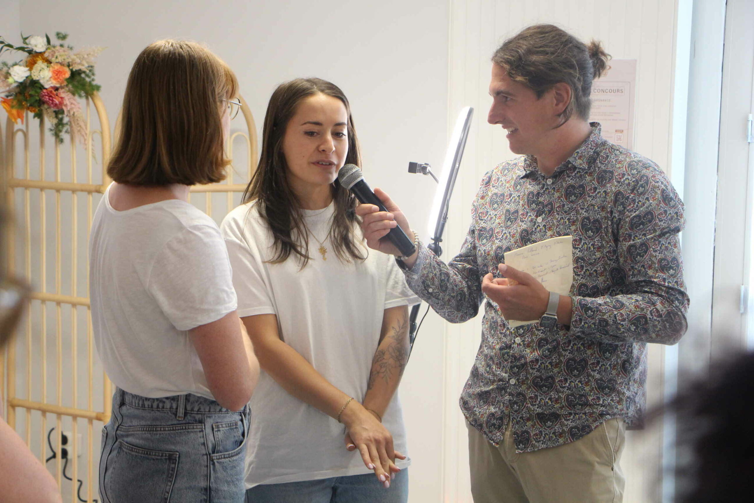 L'animateur Dominique Lowe sur la droite de la photo tient un micro en main et interview deux personnes.