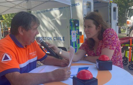 L'animatrice Chloé tend le micro à un agent de la protection civile qui répond à ses questions.
