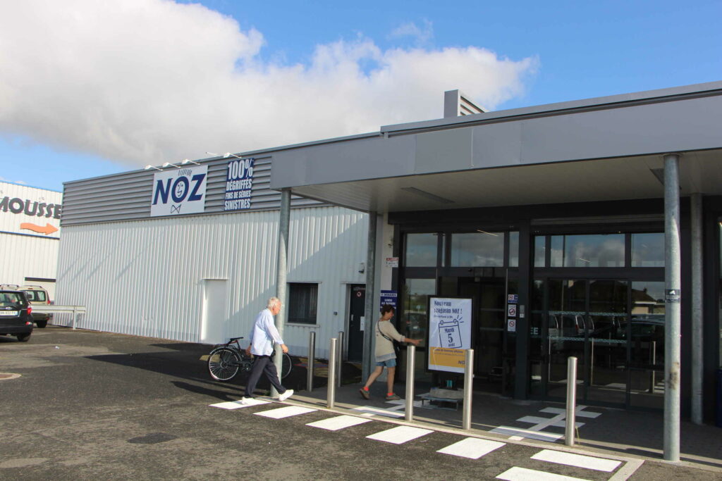 Photo de l'extérieur du nouveau magasin NOZ. Les premiers clients commencent à entrer.