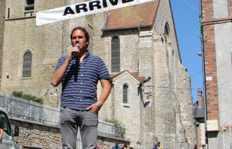 Photo de l'animateur Dominique au micro en train d'attendre les coureurs sur la ligne d'arrivée