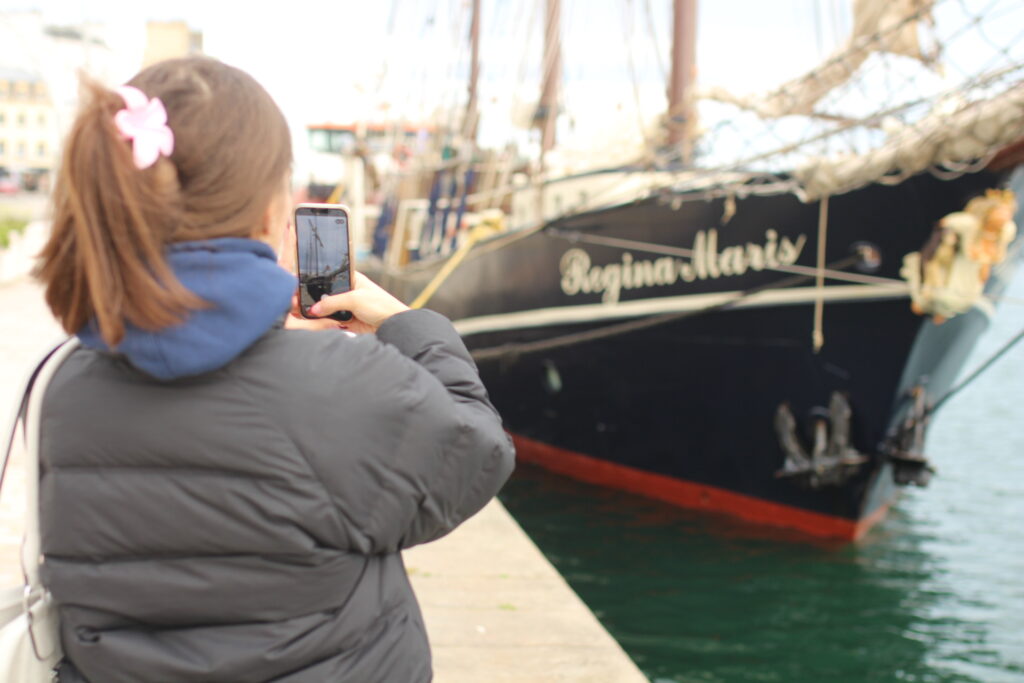 Une participante du Team Building prend une photo du Regina Maris, voilier accosté à Cherbourg-en-Cotentin.